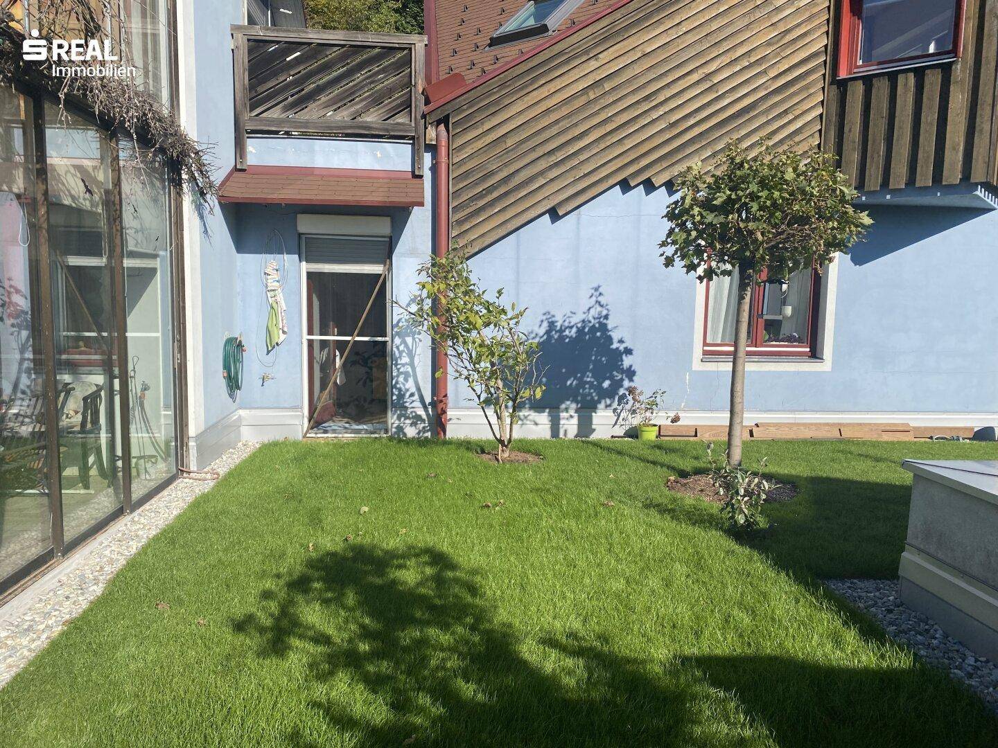 Kleiner Rasenbereich neben dem Haus mit jungen Bäumen und sonniger Lage.