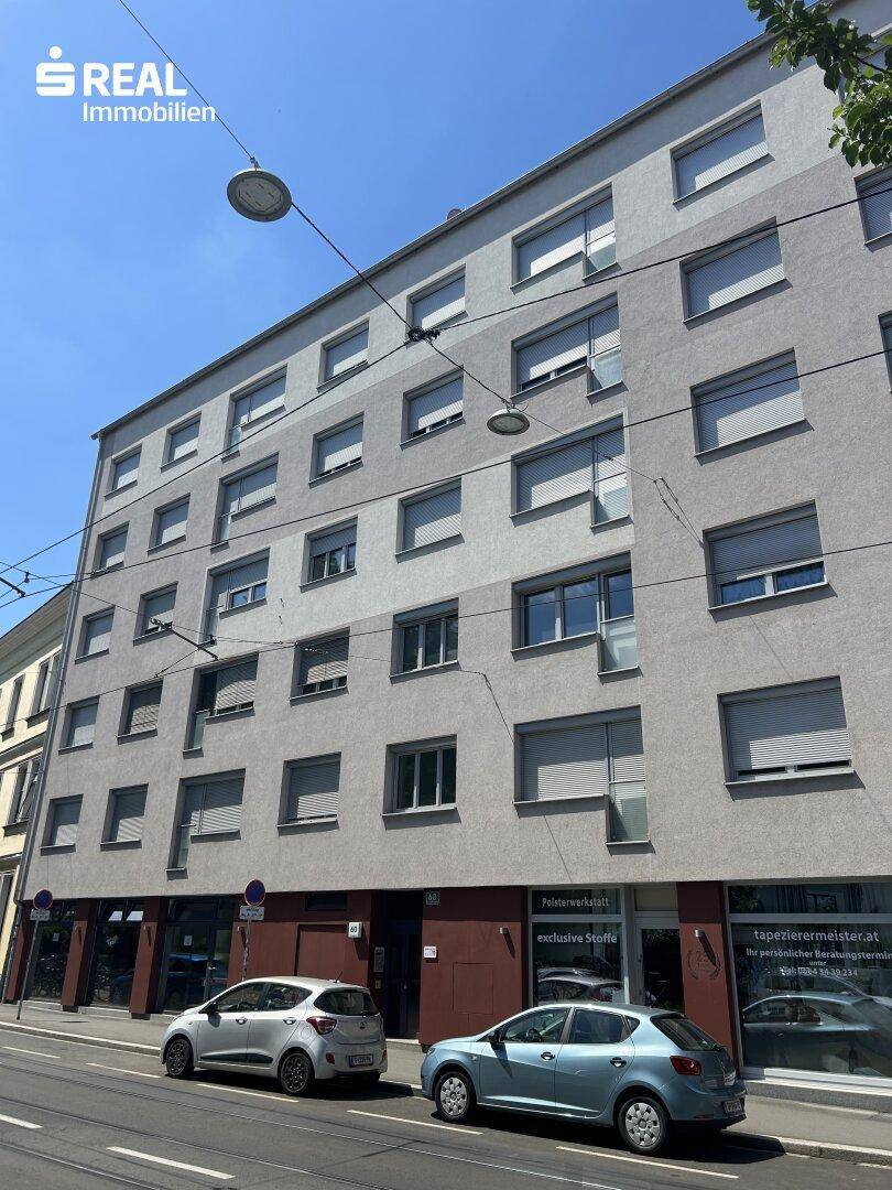 Mehrstöckiges Wohngebäude mit vielen Fenstern und Geschäften im Erdgeschoss.