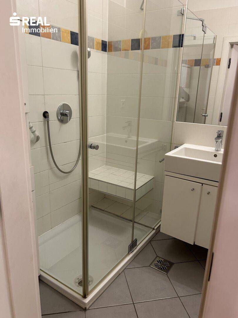 Modernes Badezimmer mit Duschkabine, Waschbecken und Fliesenboden.