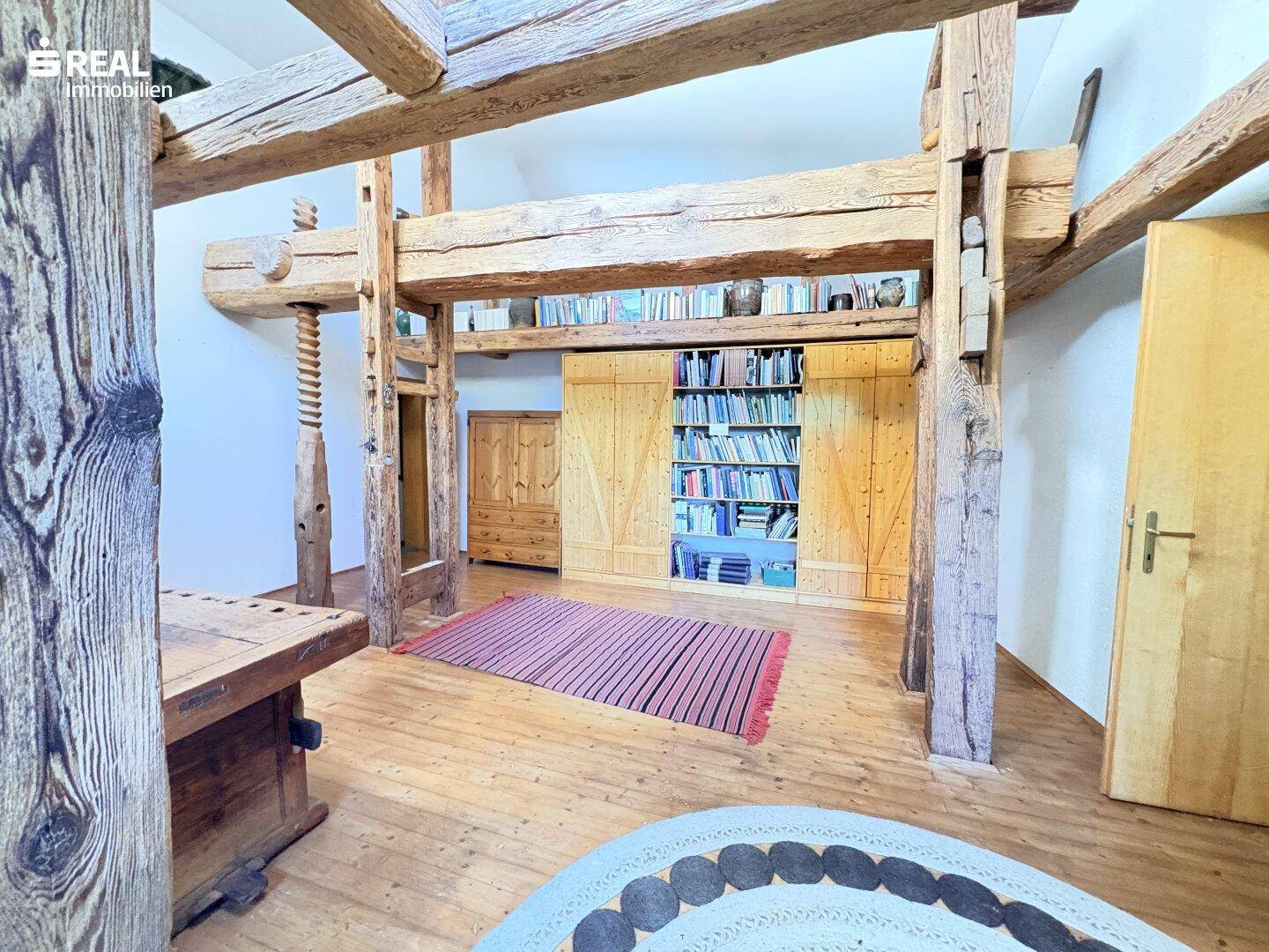 Geräumiger Wohnbereich mit beeindruckenden Holzbalken und einer integrierten Bücherwand.