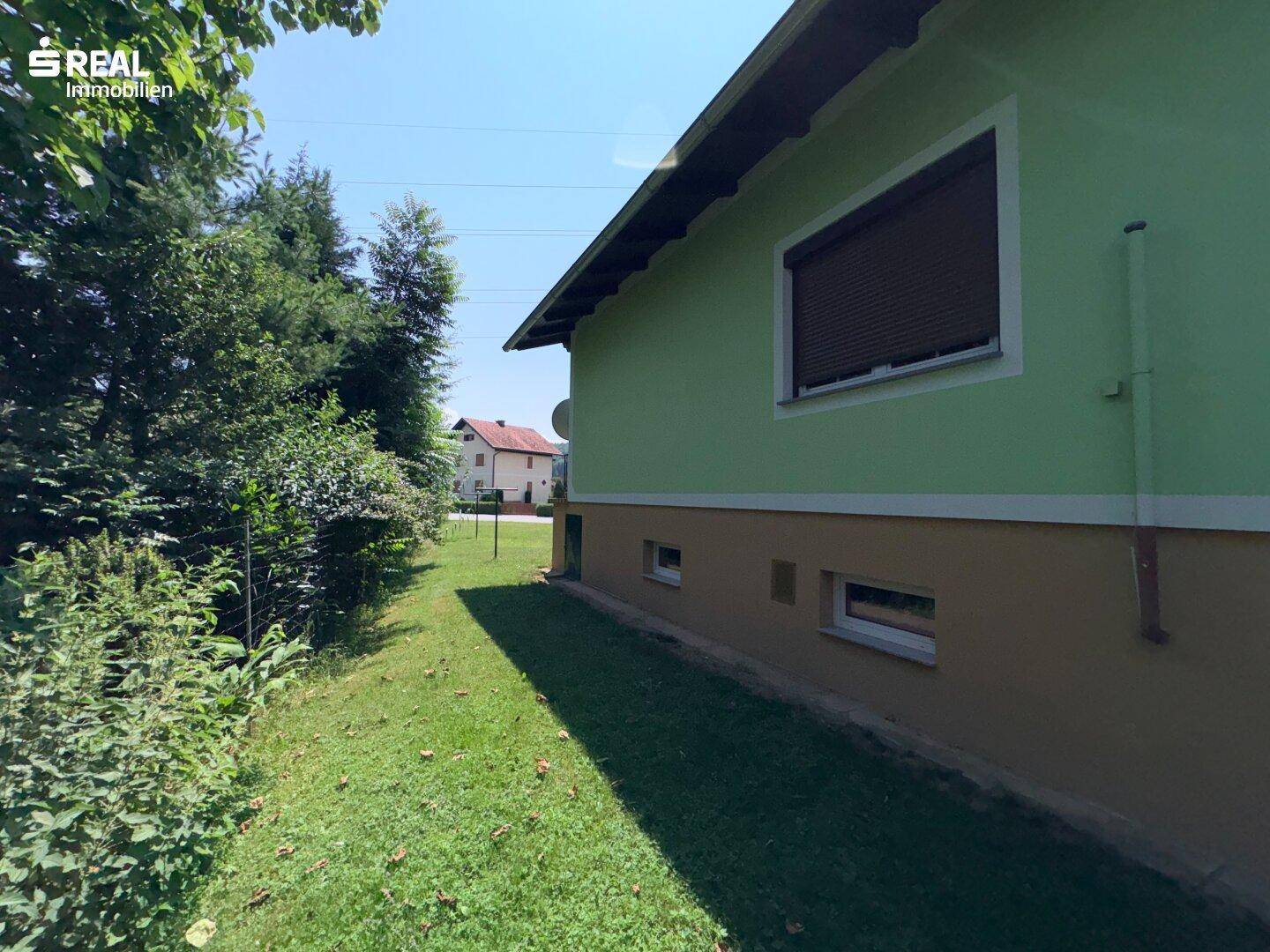 Seitenansicht des Hauses mit Garten und Blick auf die ländliche Umgebung.