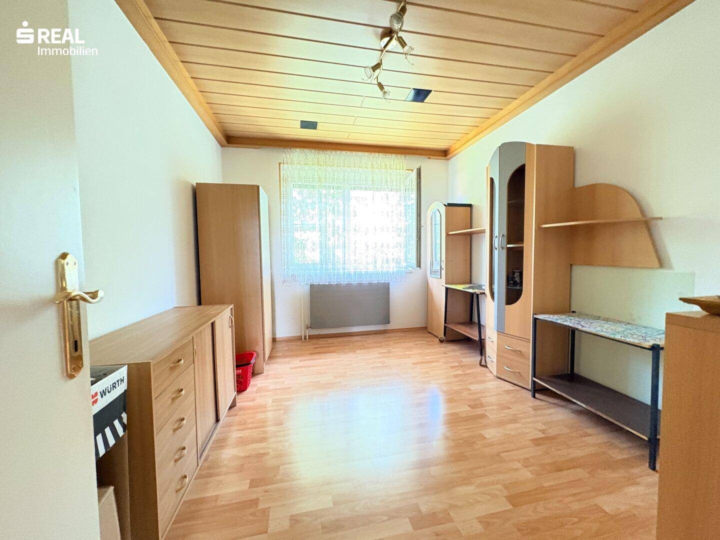 Schlafzimmer mit Holzdecke, Laminatboden und einfacher Möblierung.