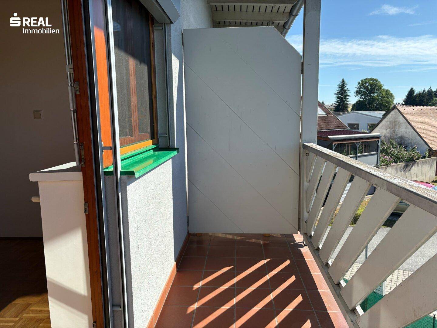 Kleiner Balkon mit Fliesenboden und Holzbalkongeländer, ideal für entspannte Stunden.