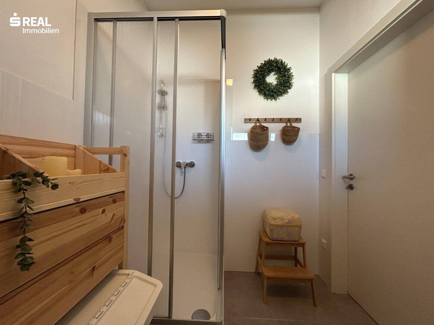 Badezimmer mit Duschkabine und schlichten Fliesen, bietet funktionalen Komfort.