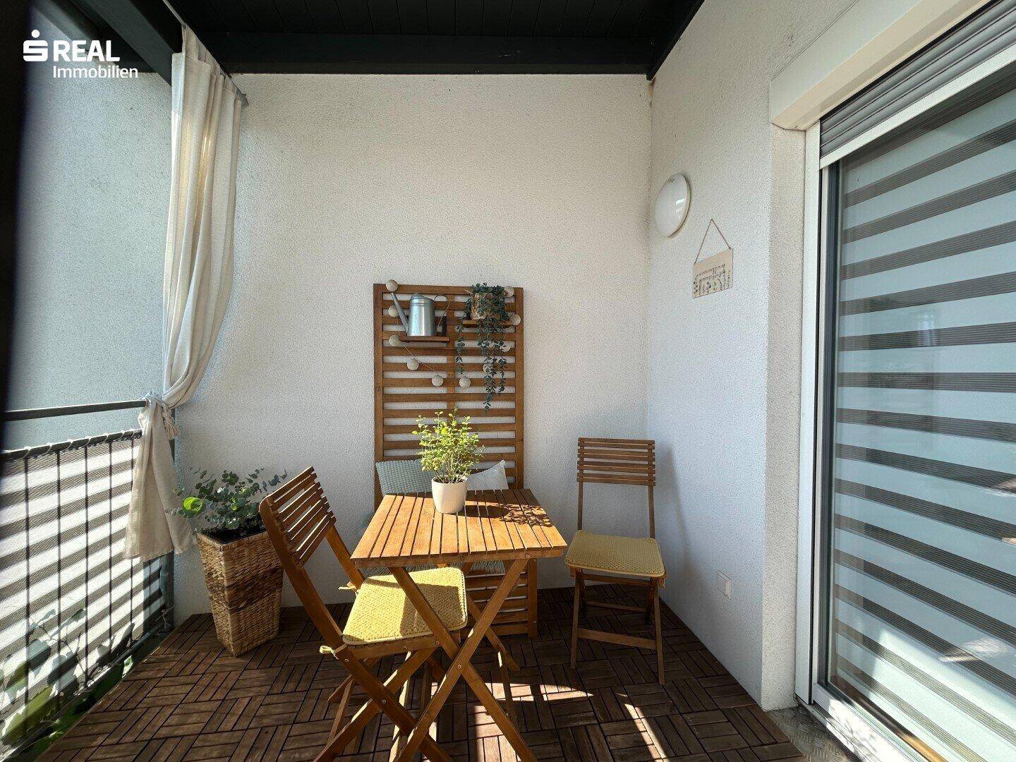 Gemütlicher Balkon mit Holztisch und Stühlen, ideal für entspannte Stunden im Freien.