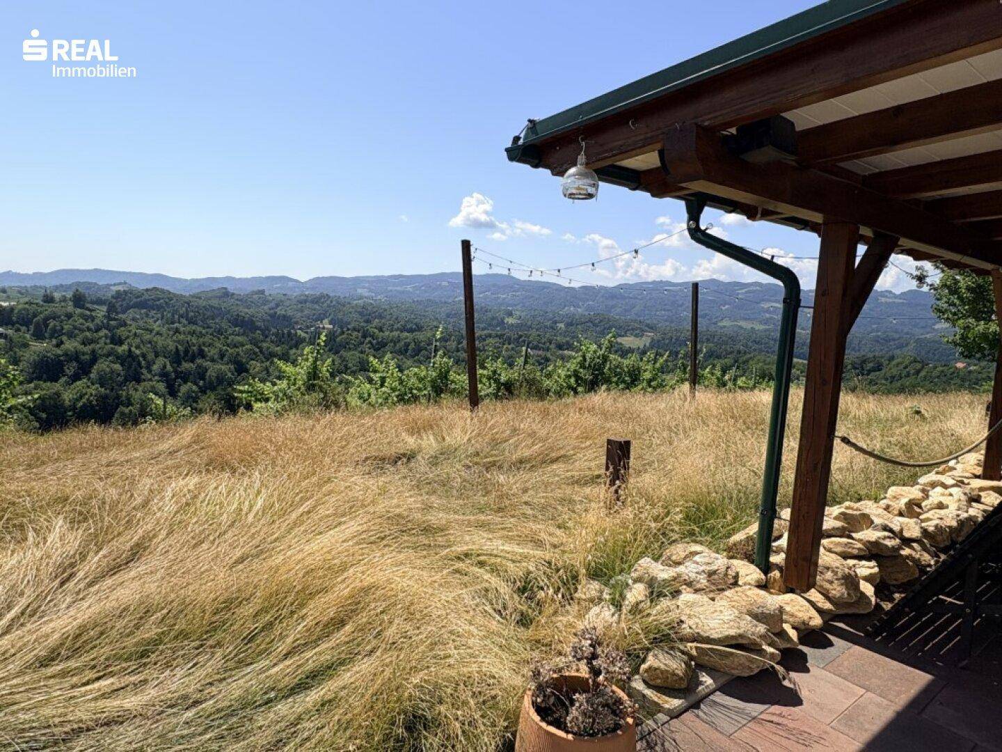 Rustikale überdachte Terrasse mit Steinmauer und Panoramablick über die Weinberge und Landschaft.