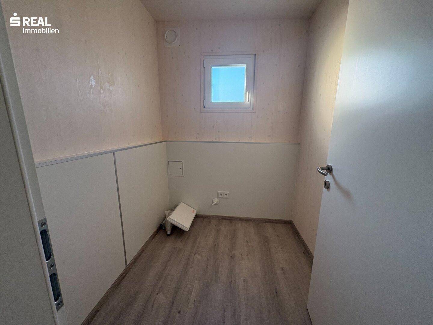 Kleiner Abstellraum mit Fenster und Laminatboden, ideal für Lagerzwecke oder als Speisekammer.