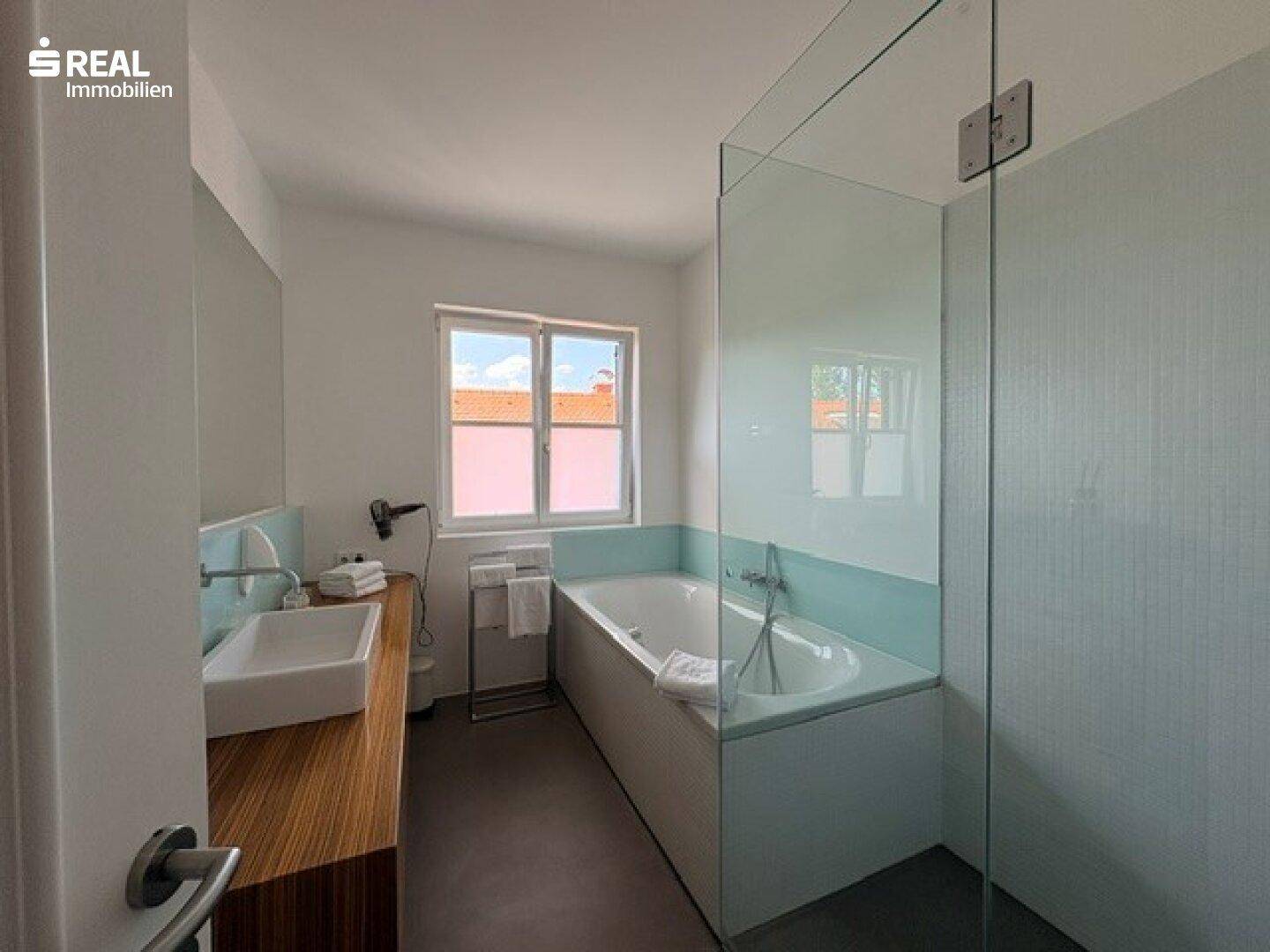 Modernes Badezimmer mit Badewanne, begehbarer Dusche und Fenster für Tageslicht.