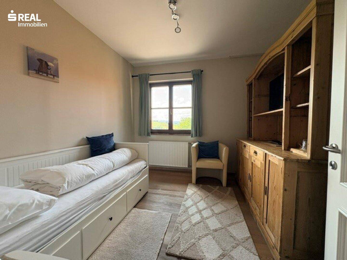 Gemütliches Schlafzimmer mit Einzelbett, großem Holzschrank und Fenster mit Ausblick.