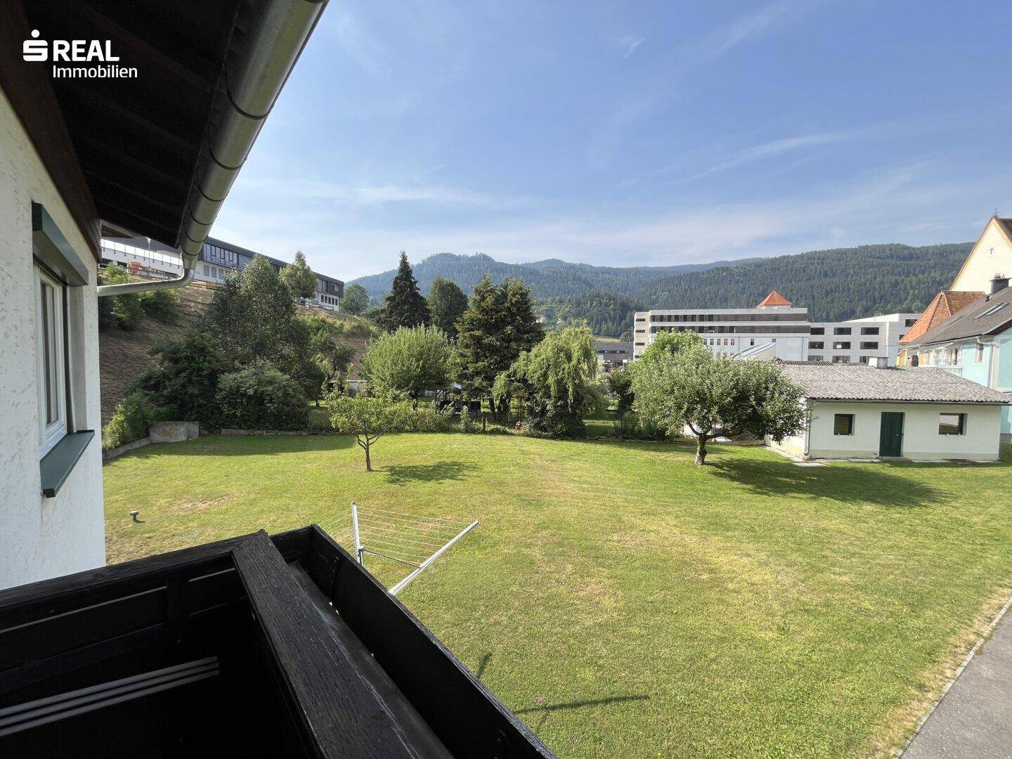 Balkon mit Blick auf den großen Garten und die umliegende Berglandschaft.