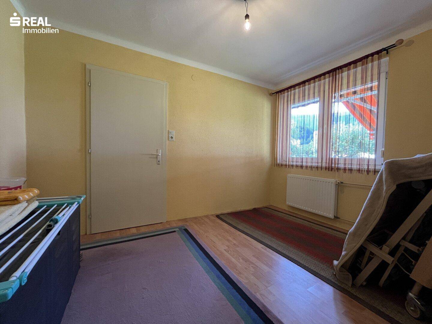 Praktischer Abstellraum mit Holzfußboden und Fenster, ideal für Lagerzwecke.