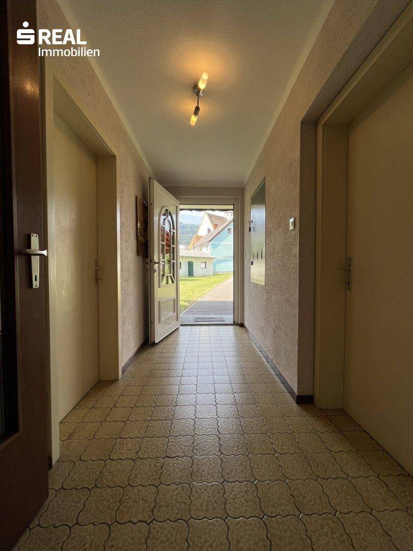 Heller Eingangsbereich mit Fliesenboden und Blick nach draußen in den Garten.