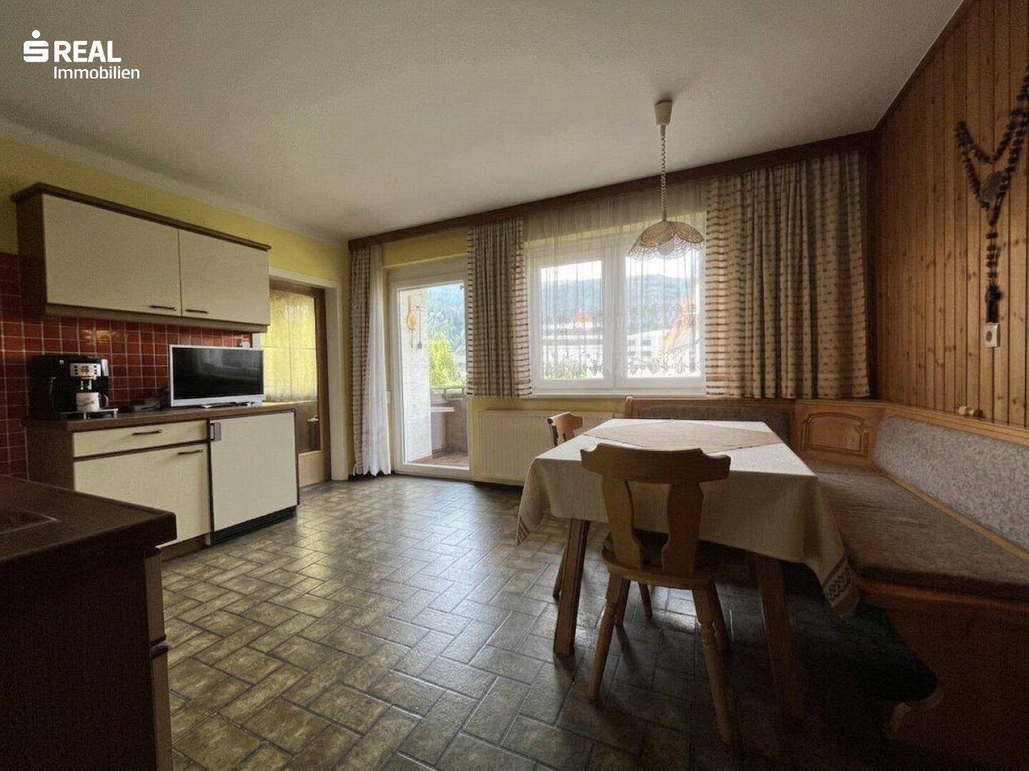 Traditionelle Küche mit Essbereich, Holzvertäfelung und Blick ins Grüne.