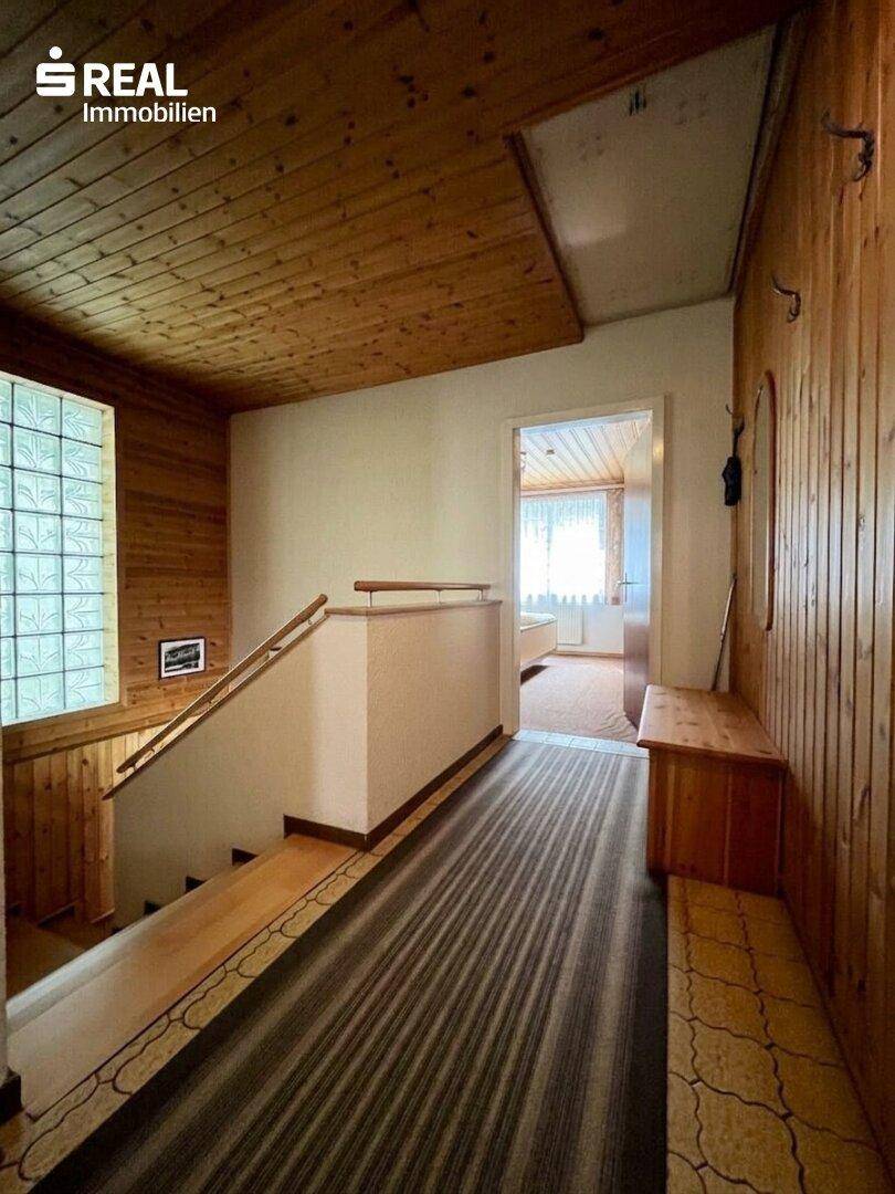 Flur mit Holzvertäfelung, Treppe und Glasbausteinwand für natürliches Licht.