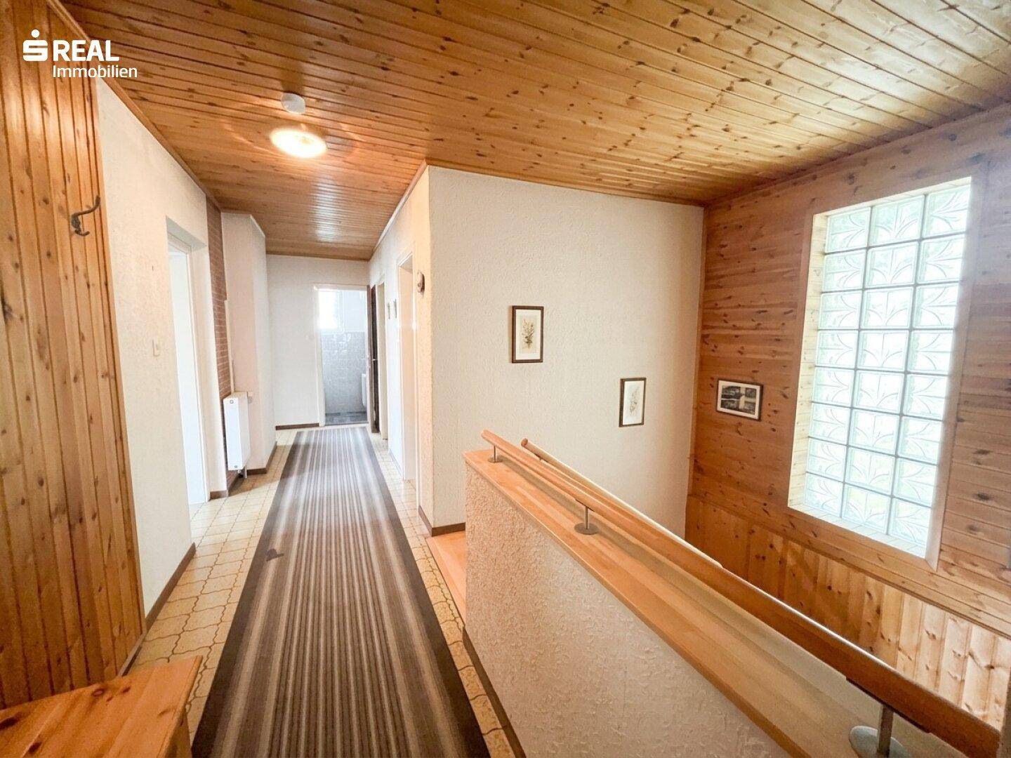 Geräumiger Flur mit Holzdecke und -wänden, Treppe und Glasbaustein-Fenster.