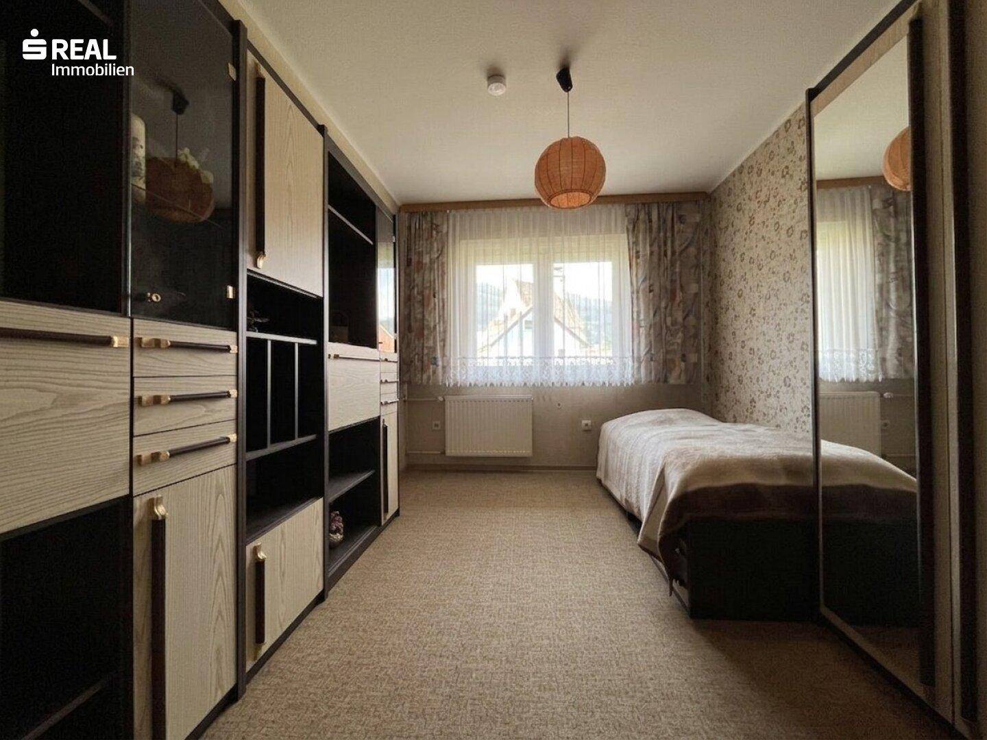 Schlafzimmer mit Einzelbett, großem Kleiderschrank und Teppichboden.