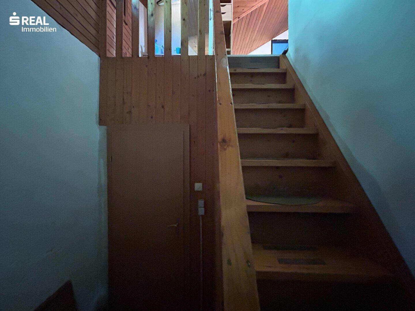 Holztreppe führt in die obere Etage, umgeben von Holzverkleidung.