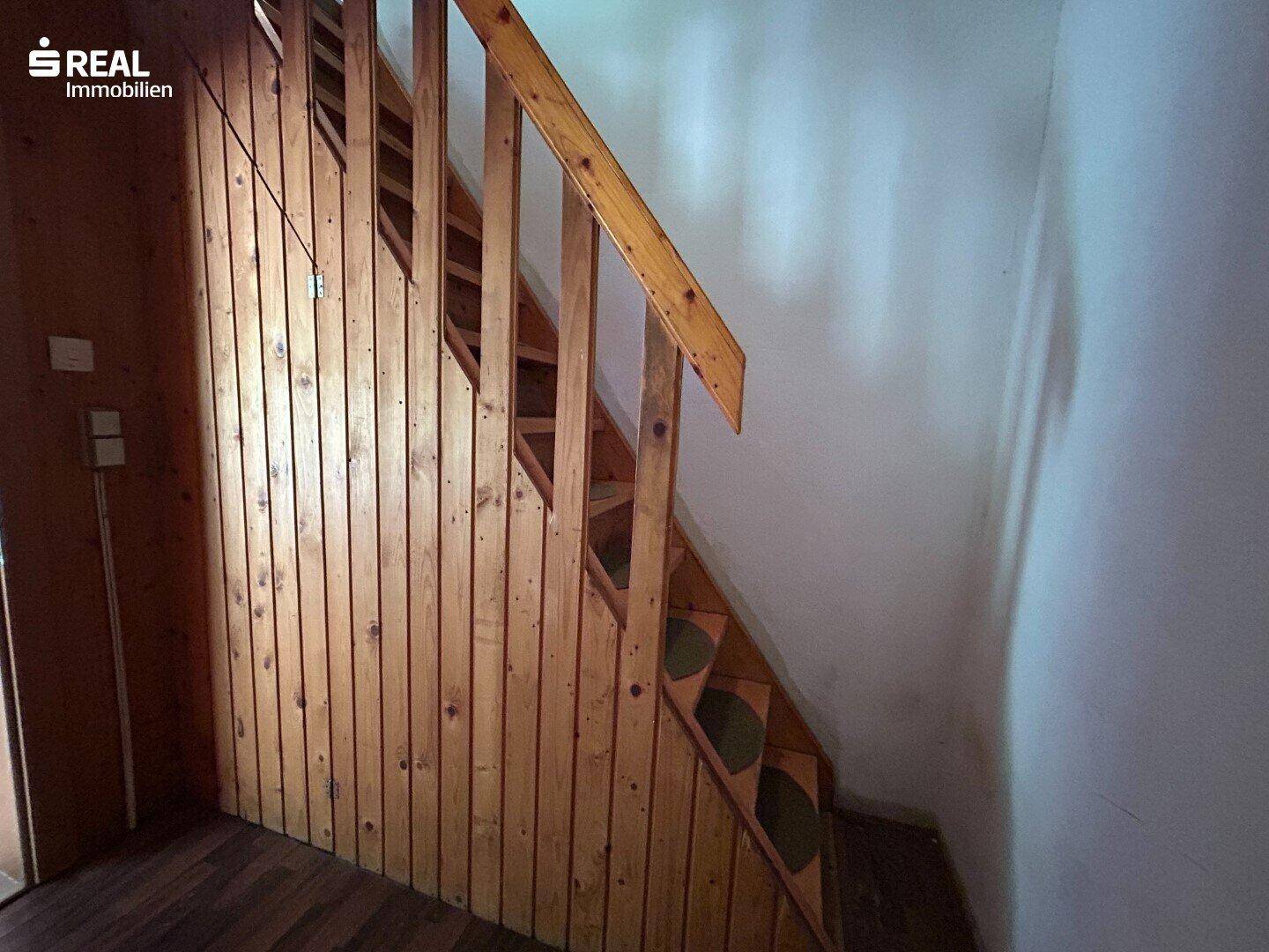 Detailansicht der Holztreppe mit Geländer und Holzverkleidung an der Wand.