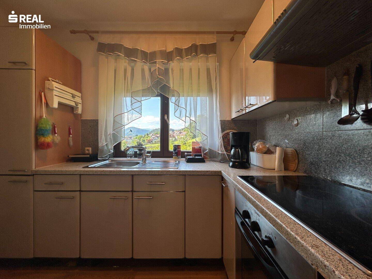 Helle Küche mit Arbeitsplatte, Spüle und Fenster mit weitem Ausblick.