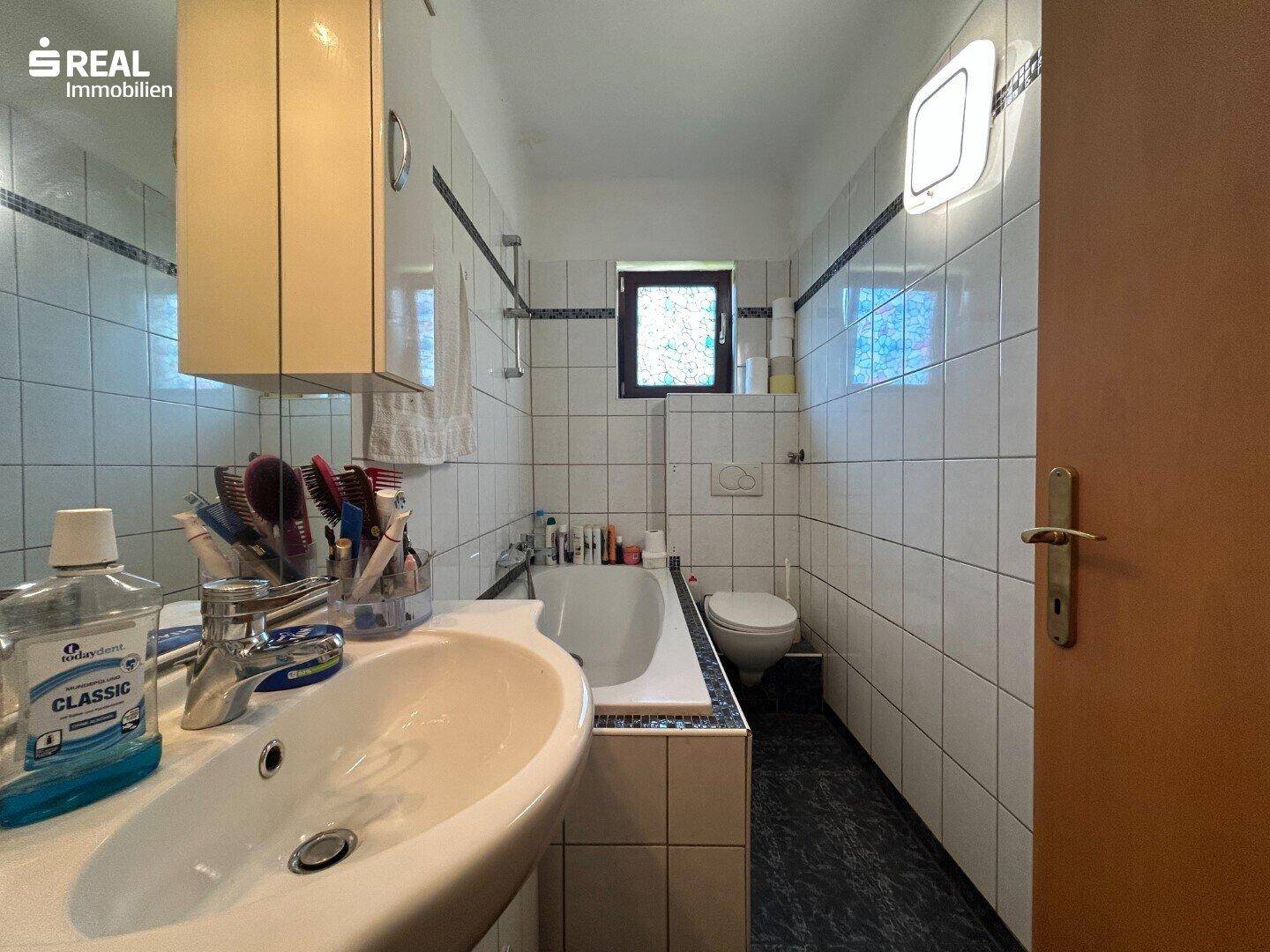 Badezimmer mit Badewanne, WC, Waschbecken und Fliesen in klassischem Design.