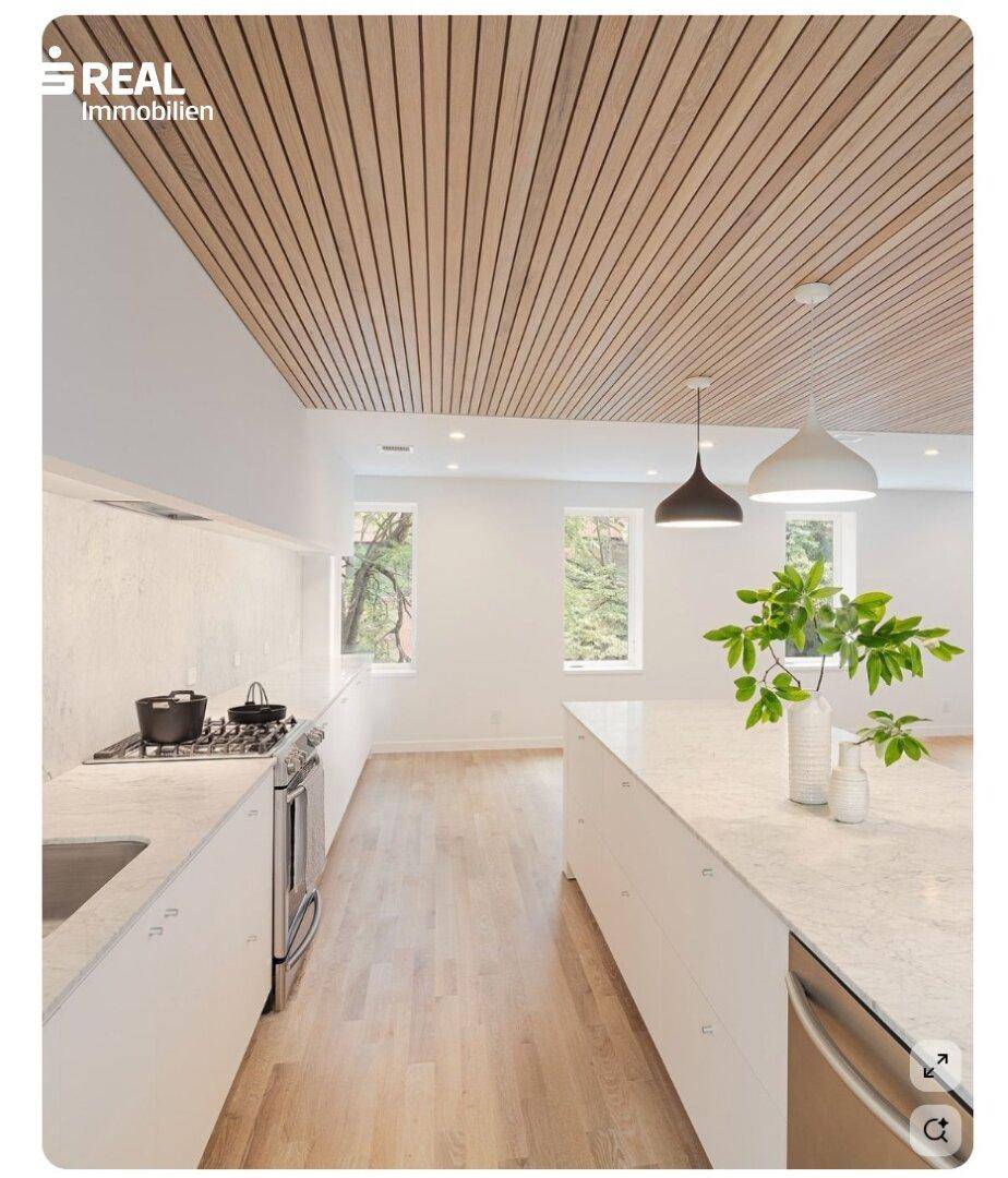 Moderne Küche mit weißer Einrichtung, Holzlamellendecke, Kücheninsel und viel natürlichem Licht.
