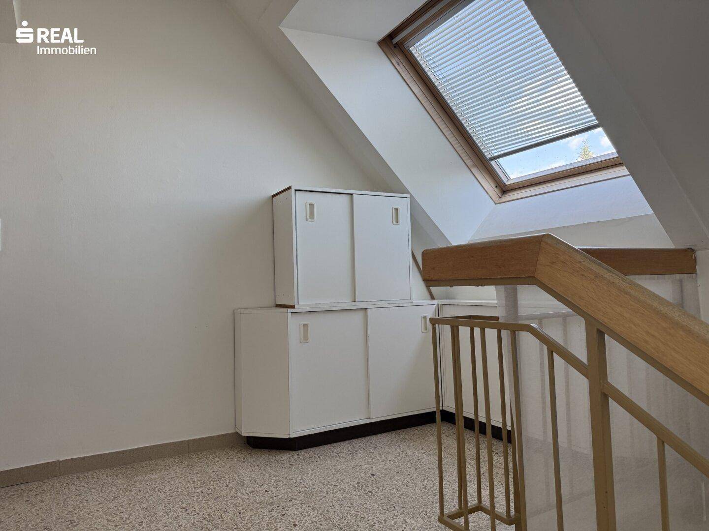 Treppenhausbereich mit Dachfenster, Einbauschränken und Terrazzoboden.