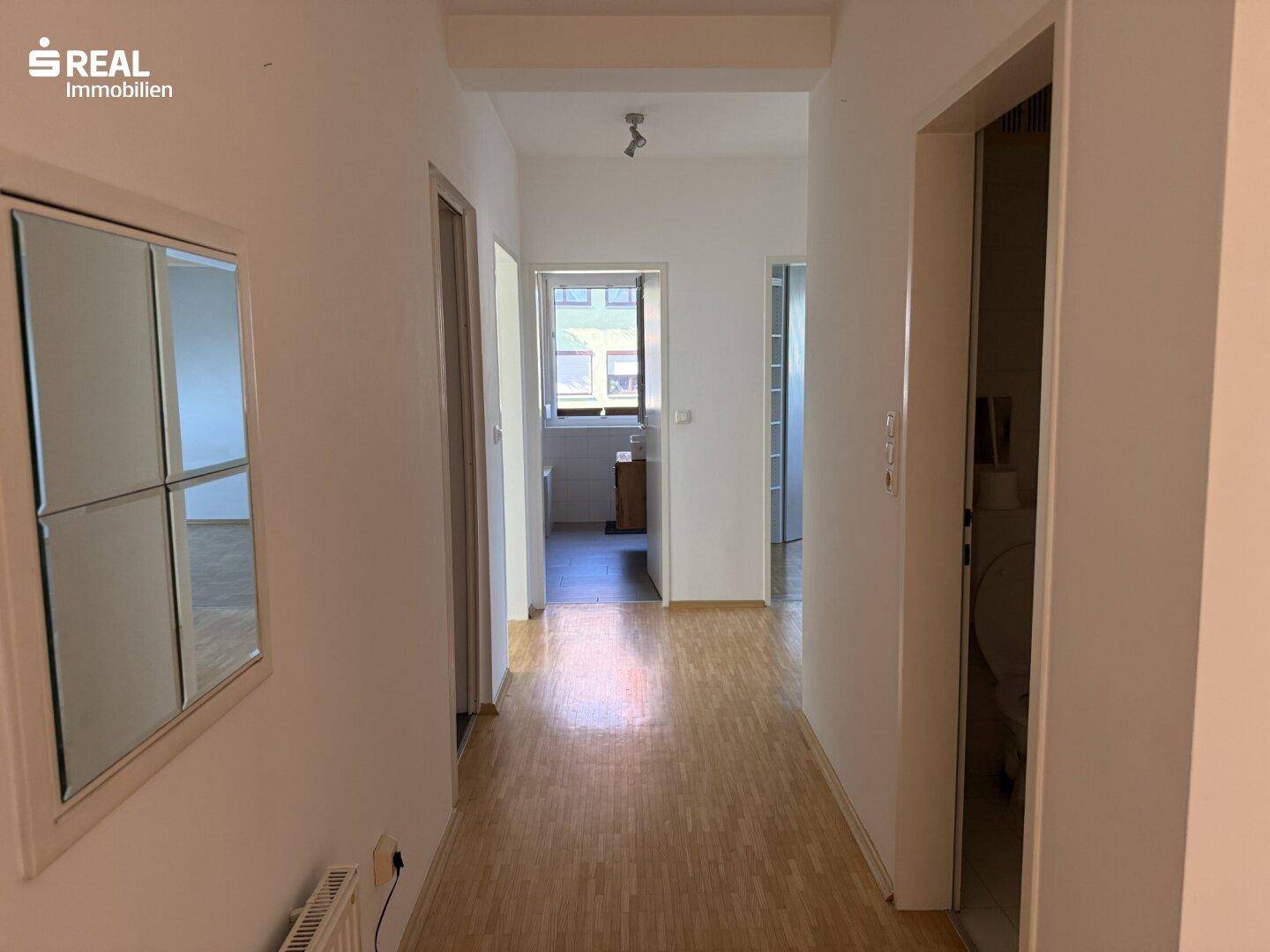 Heller Flur mit Holzboden und Zugang zu verschiedenen Zimmern der Wohnung.