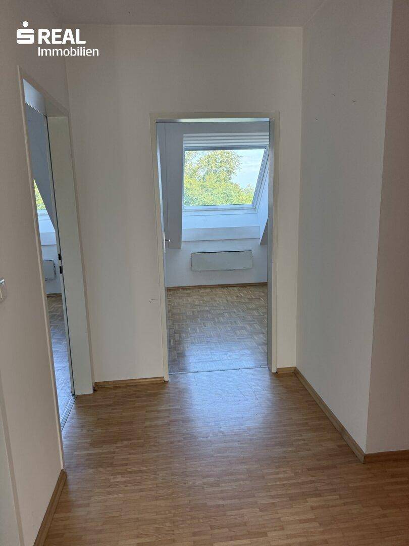 Heller Flur mit Parkettboden und Blick in ein weiteres Zimmer mit Dachfenster.