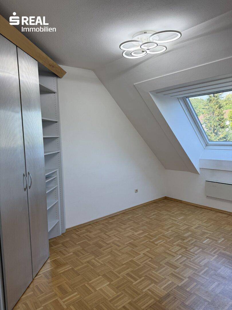 Helles Schlafzimmer im Dachgeschoss mit Parkettboden, Dachfenster und Einbauschrank.