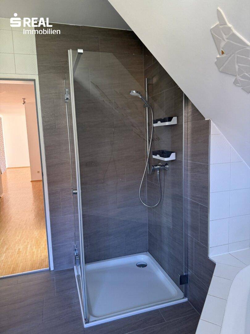 Moderne Duschkabine mit Glaswänden und Fliesen in dunklem Grau im Badezimmer.