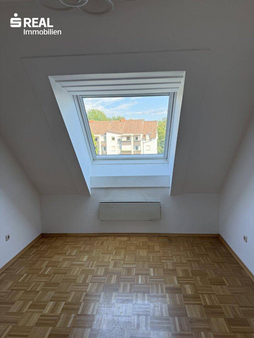 Geräumiges Schlafzimmer mit Parkettboden und großem Dachfenster für viel Tageslicht.