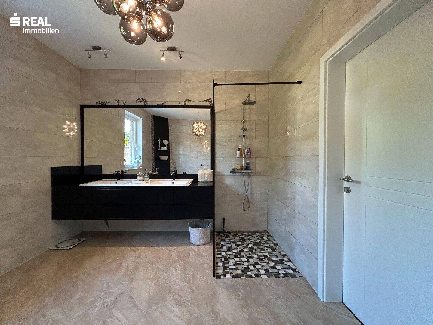 Modernes Badezimmer mit ebenerdiger Dusche, Doppelwaschbecken und großen Fliesen.