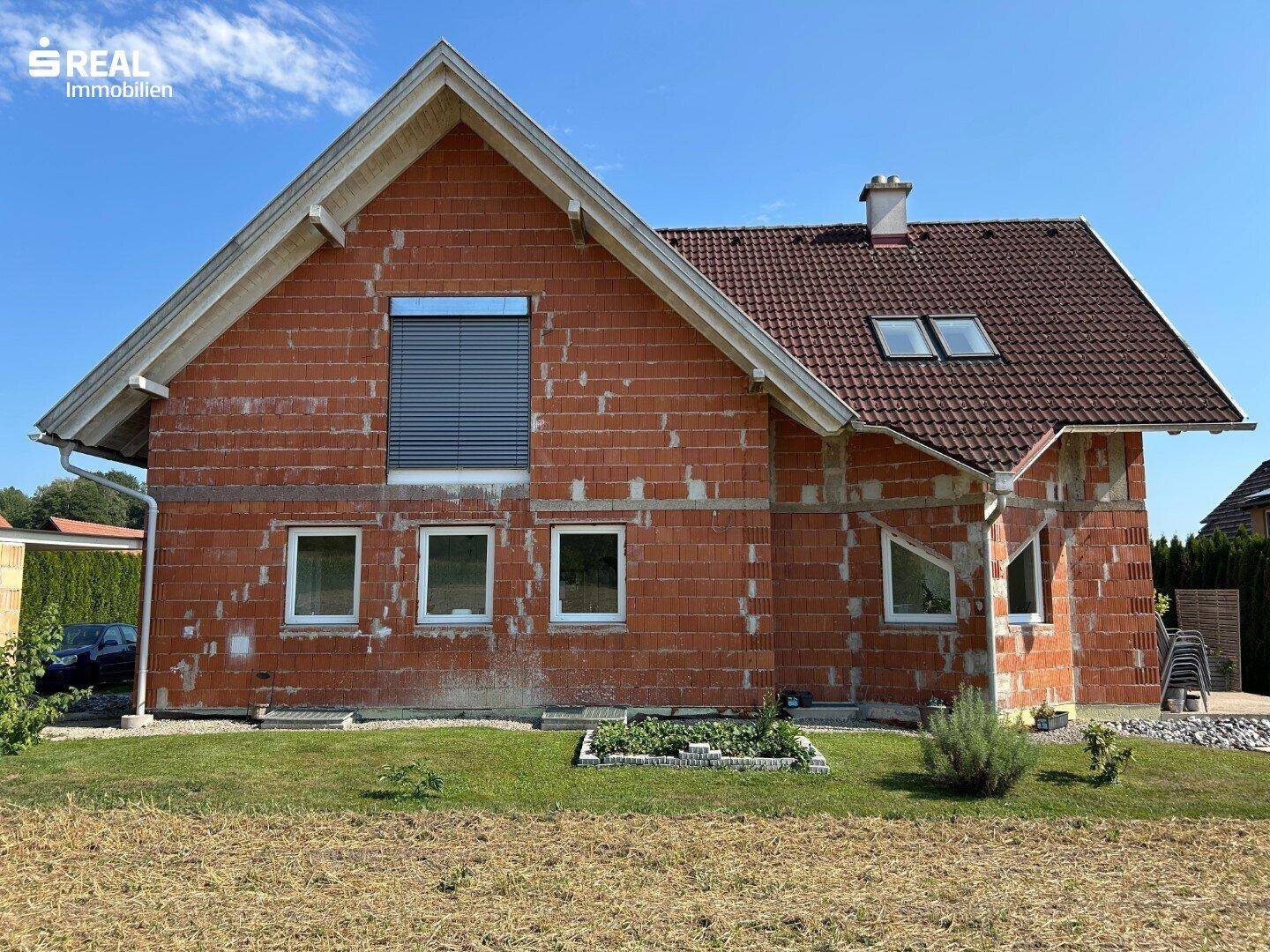 Neubau im Rohbauzustand mit Ziegelmauerwerk und Satteldach.