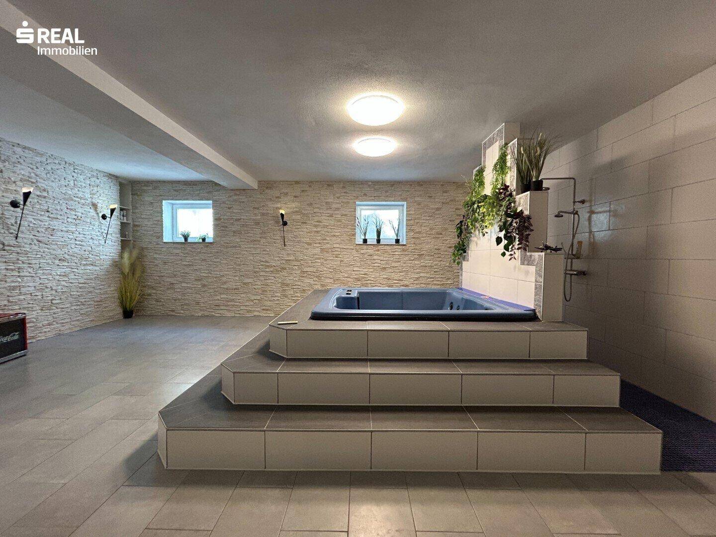 Geräumiger Wellnessbereich mit Whirlpool und Steinwand-Akzenten.