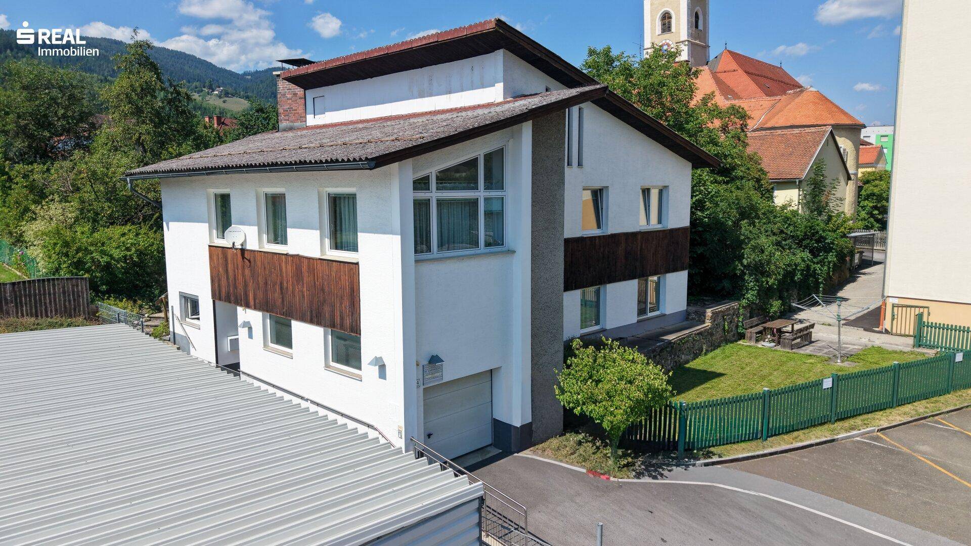Seitenansicht des Hauses mit angrenzendem Carport und Blick auf die Kirche im Hintergrund.