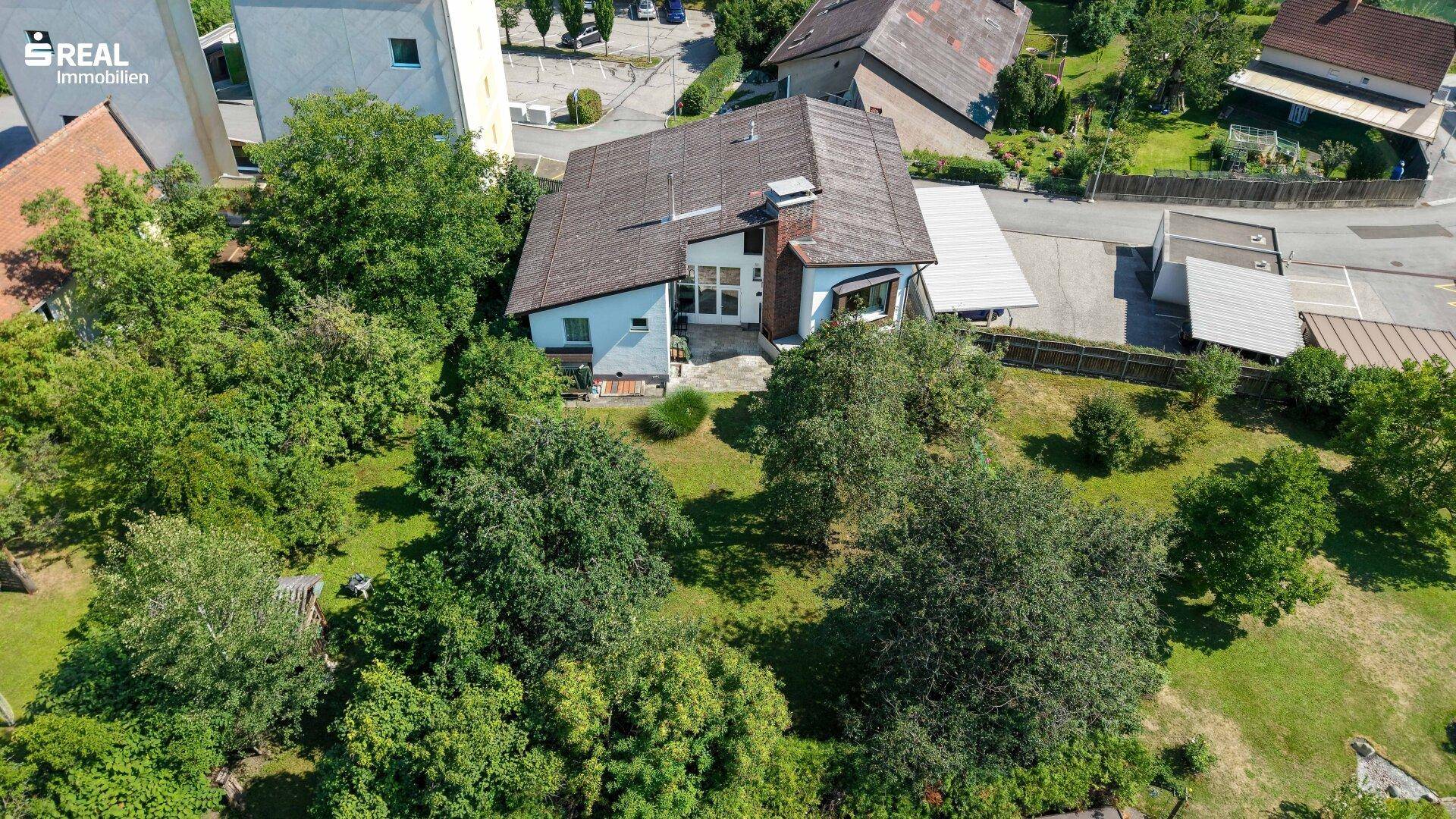 Weitläufige Luftaufnahme des Anwesens mit großem Garten und umgebender Naturlandschaft.