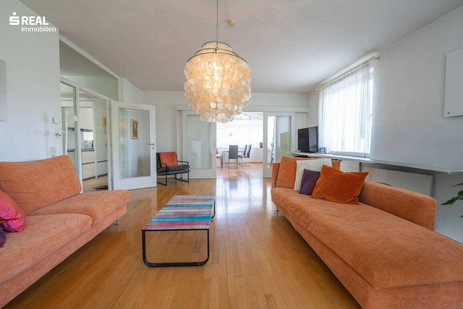 Geräumiges Wohnzimmer mit Holzboden, gemütlichen Sofas und Durchgang zum Essbereich.