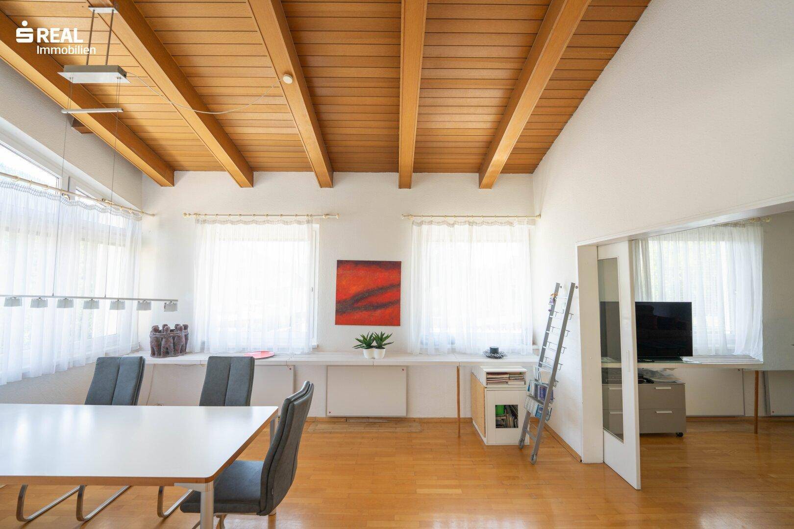 Geräumiger Essbereich mit sichtbaren Holzbalken an der Decke und viel Tageslicht.