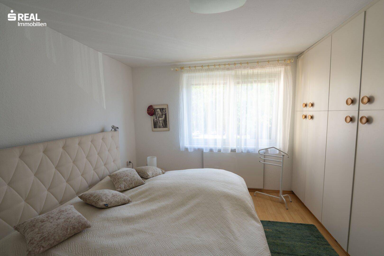 Gemütliches Schlafzimmer mit großem Bett, Einbauschränken und hellem Fenster.