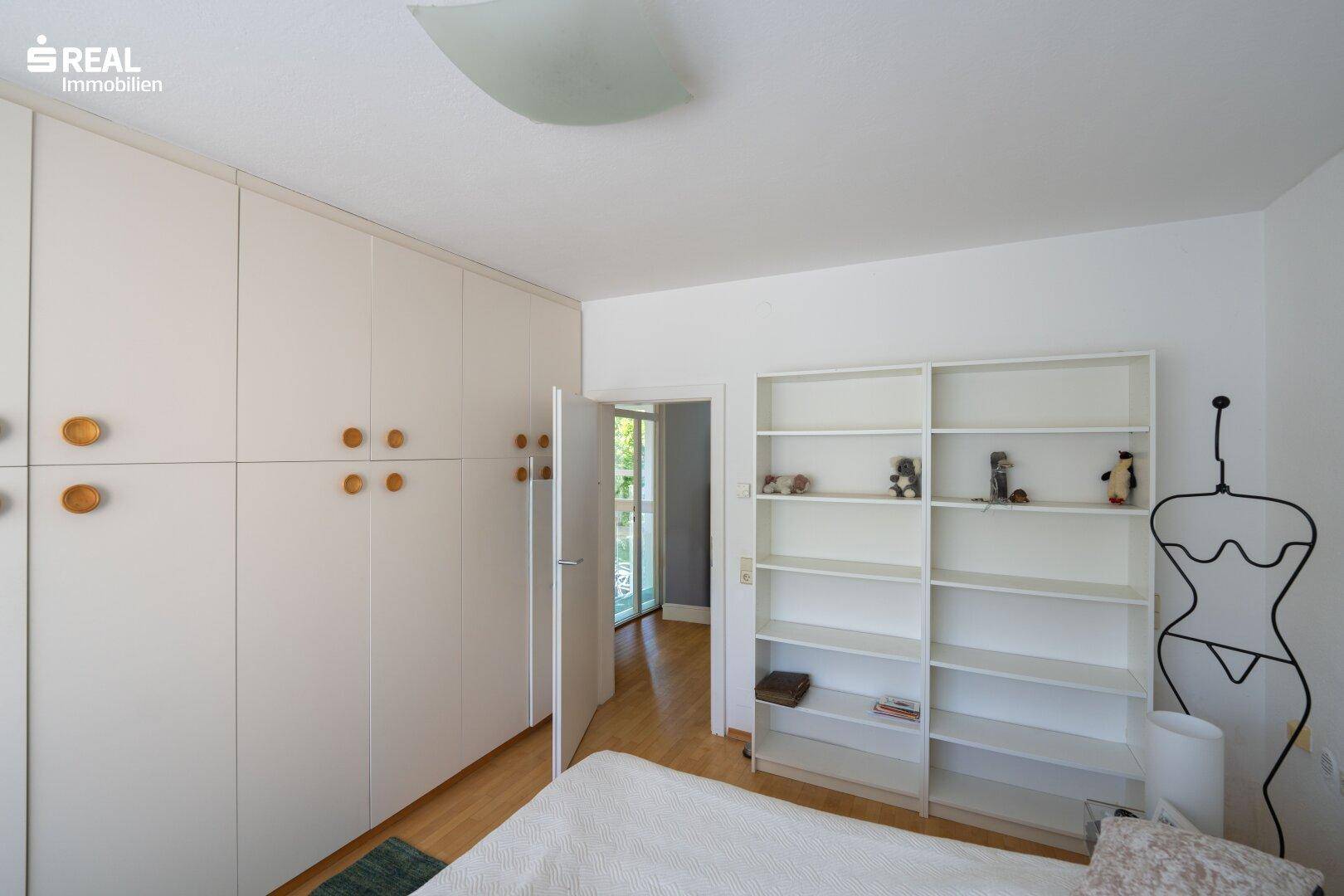 Schlafzimmer mit Einbauschränken und Regal, bietet direkten Zugang zu einem weiteren Raum.
