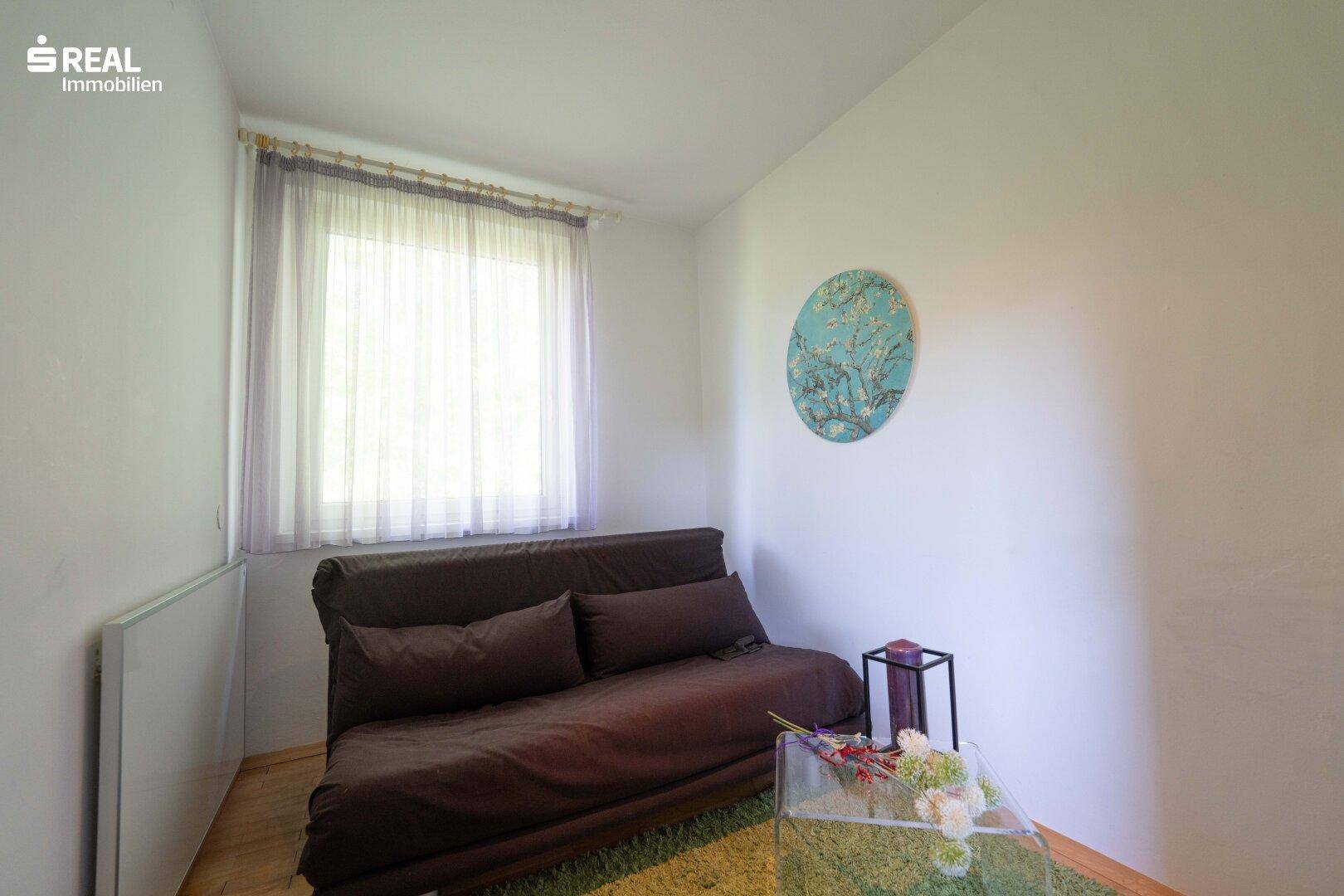 Kleines Schlafzimmer oder Gästezimmer mit Schlafsofa und Fenster, gemütlich eingerichtet.