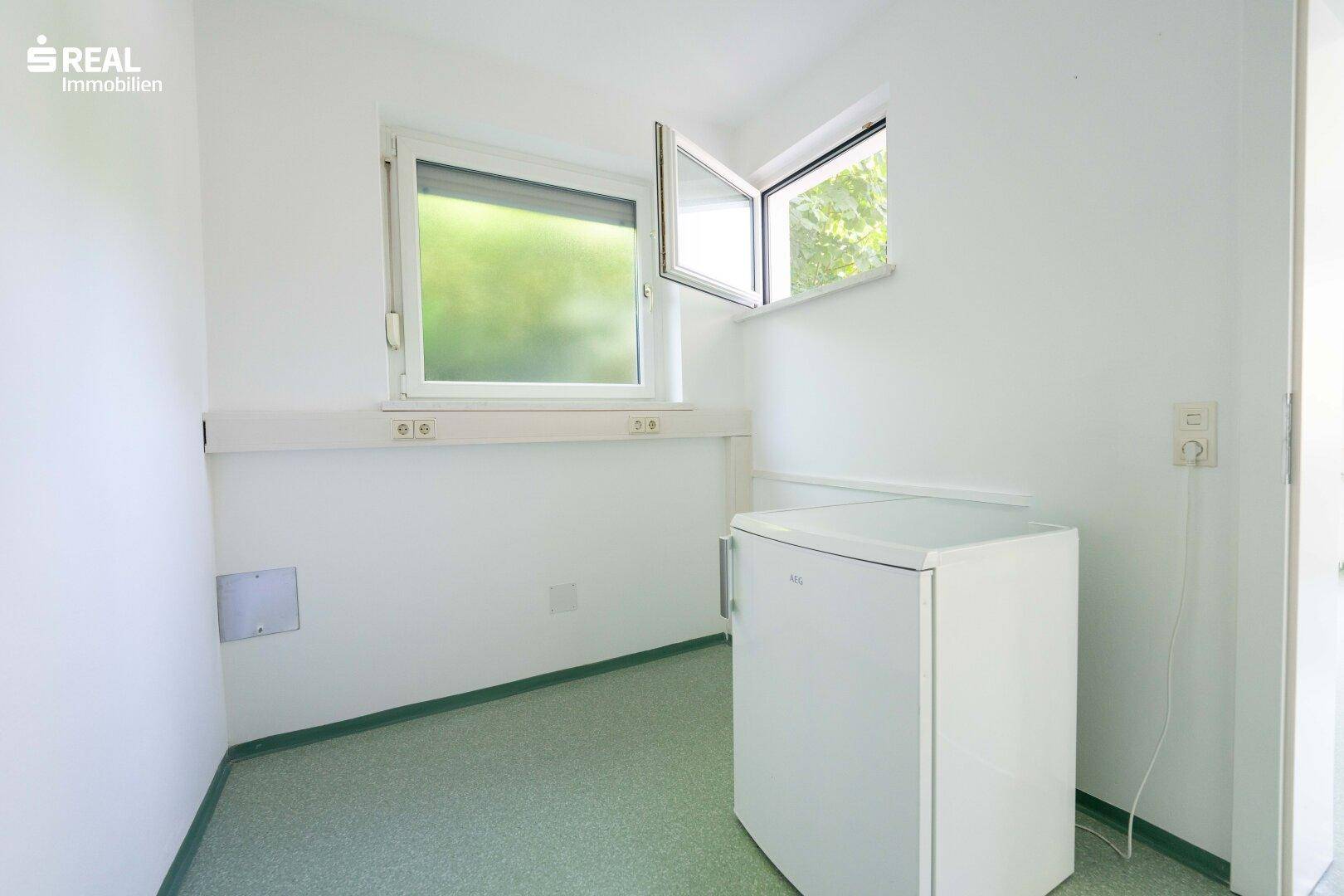 Heller Hauswirtschaftsraum mit Fenster und Kühlschrank, ideal für zusätzliche Lagerung.