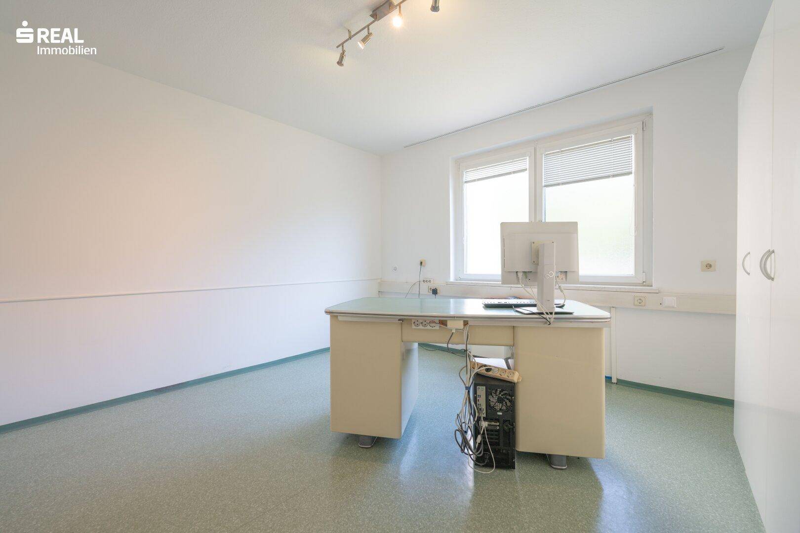 Geräumiges Büro mit großem Fenster, Schreibtisch und ausreichend Platz für Arbeitsgeräte.