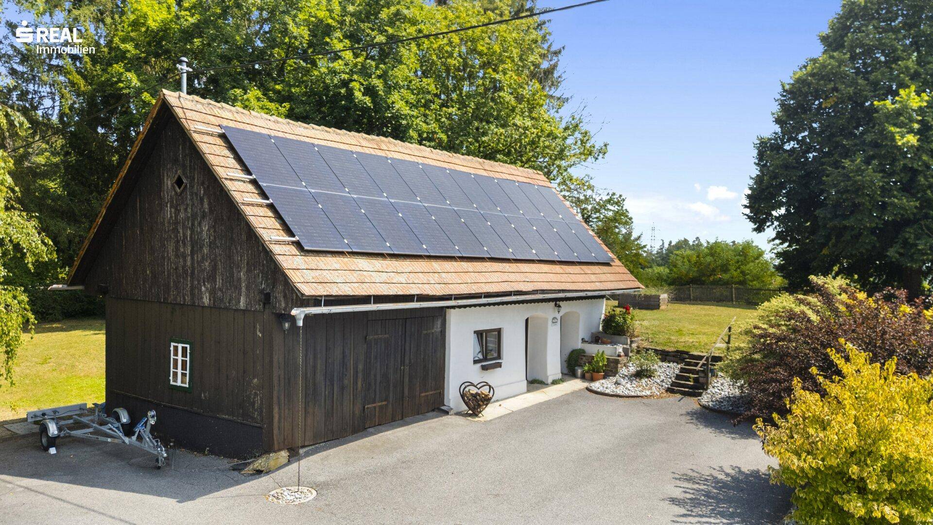 Nebengebäude mit Photovoltaikanlage auf dem Dach und traditioneller Holzfassade.