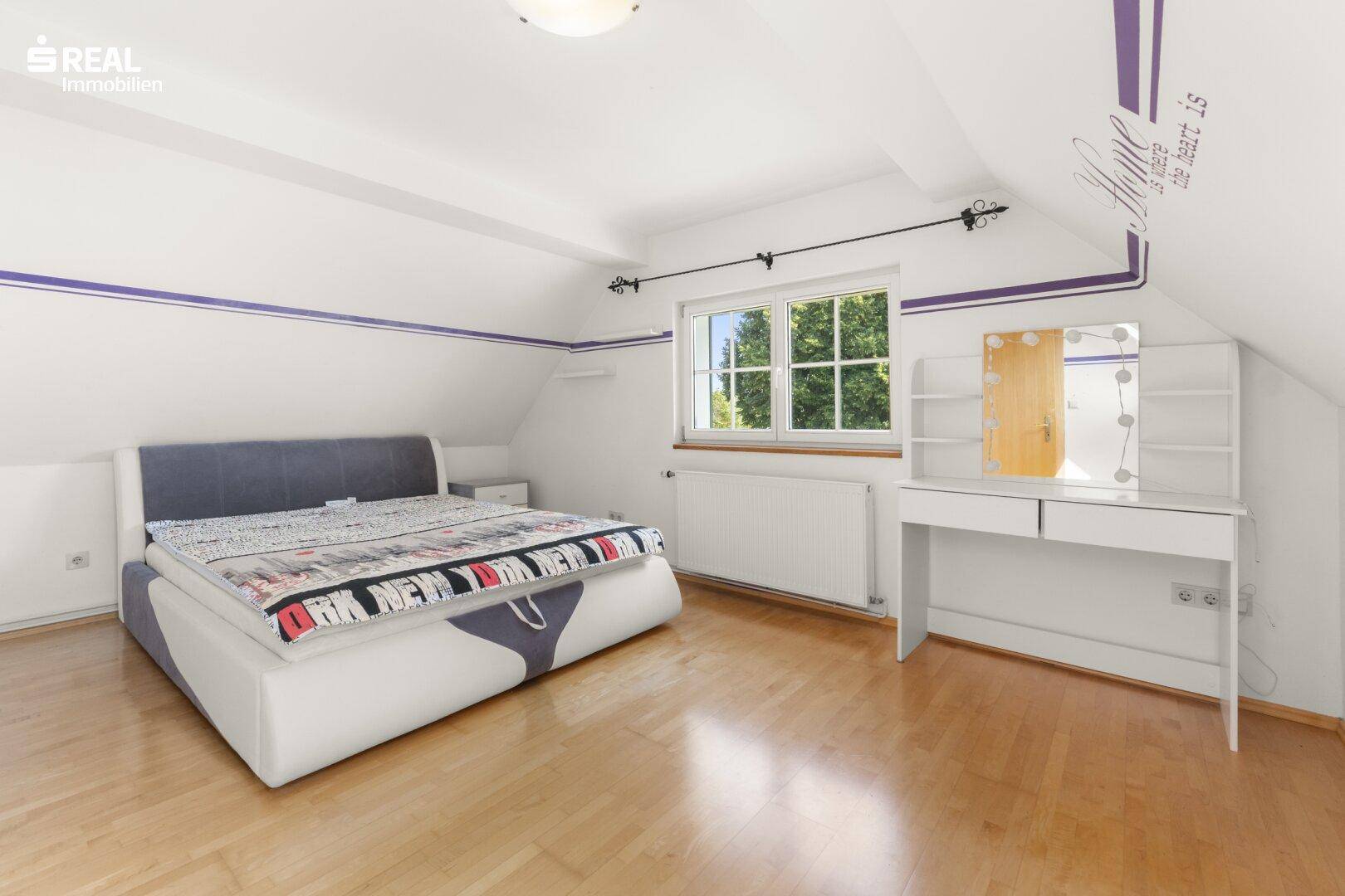 Helles Schlafzimmer im Dachgeschoss mit Dachschrägen, Holzboden und einem Schminktisch.