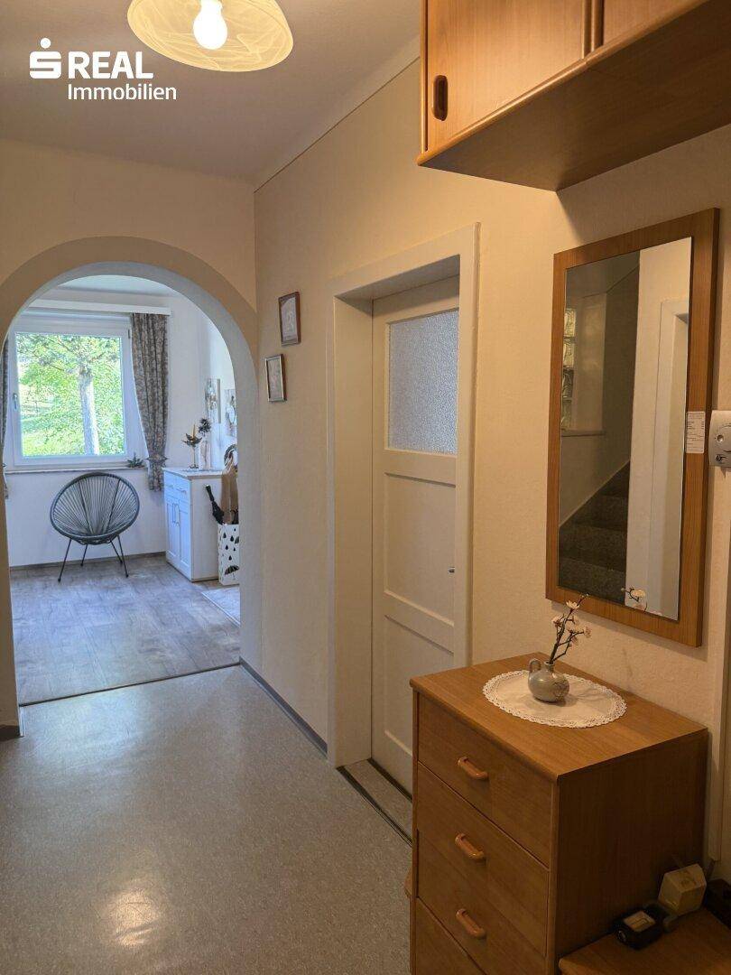 Gemütlicher Flur mit Holzkommode, Spiegel und Blick in den Eingangsbereich.