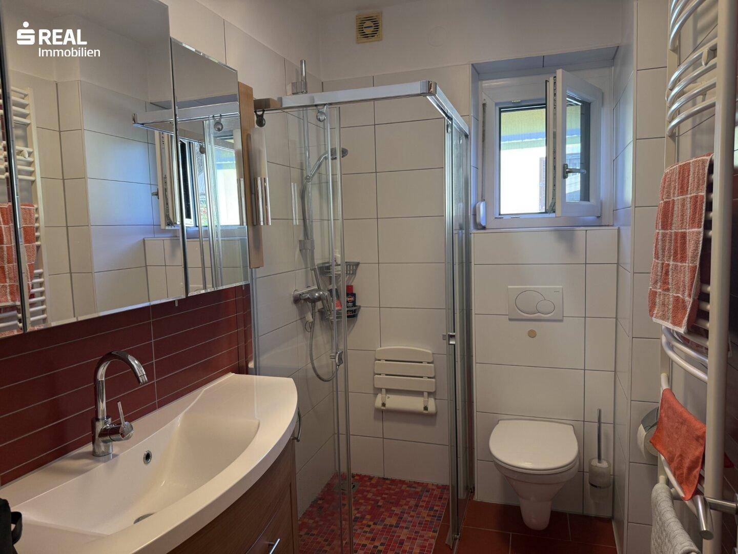 Modernes Badezimmer mit Dusche, Waschbecken und beheiztem Handtuchhalter.