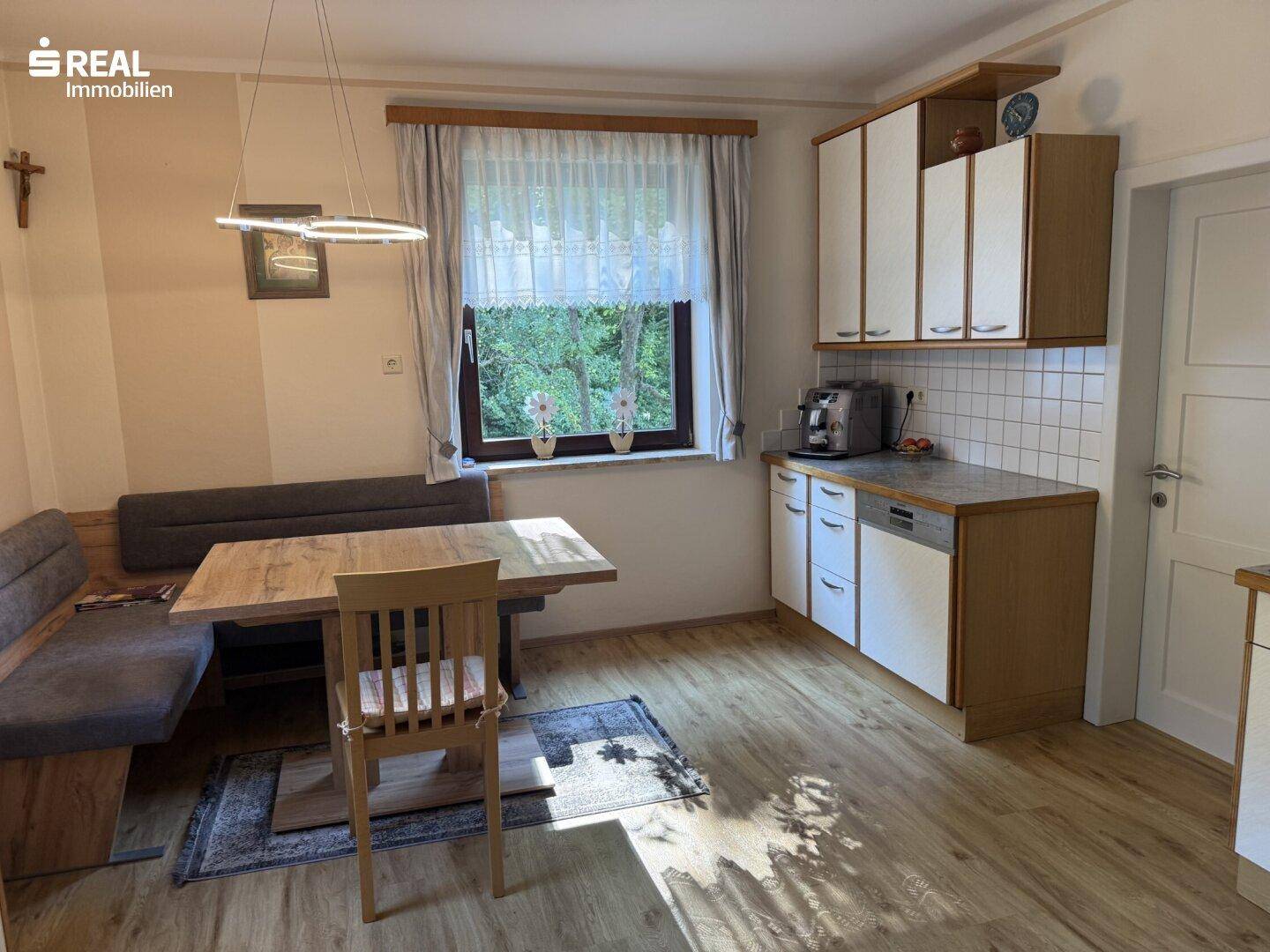 Helle Wohnküche mit Essbereich, Holztisch und Blick ins Grüne.