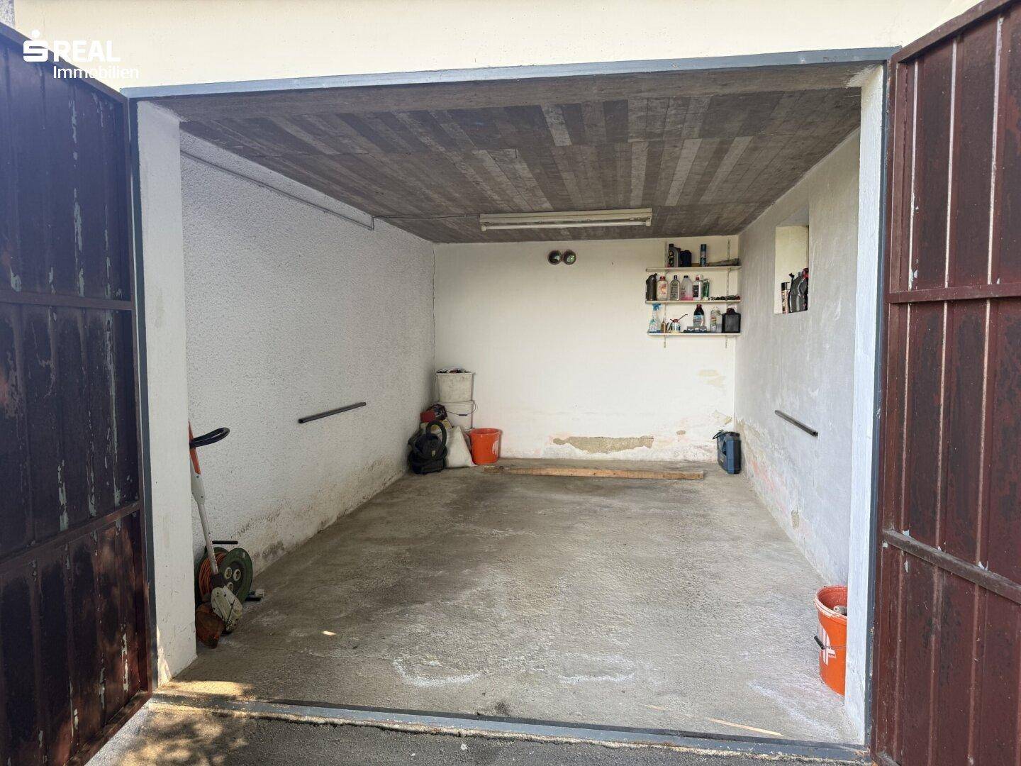 Geräumige Garage mit Betonboden und ausreichend Platz für ein Fahrzeug und Lagerung.