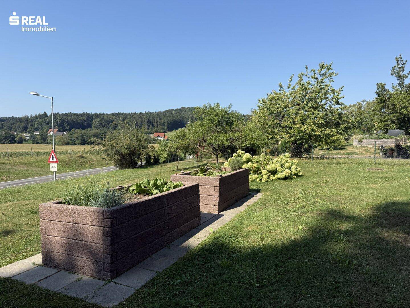 Gartenbereich mit Hochbeeten und weitem Blick über die ländliche Umgebung.